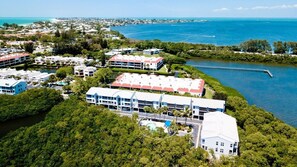 Vue aérienne d’un hôtel situé sur la côte, composé de plusieurs bâtiments, d’une piscine et d’une jetée qui s’avance dans l’eau.
