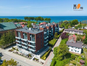 Un moderno complejo de apartamentos con varias construcciones, un césped cuidado y vistas al mar.