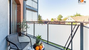 A balcony with a wicker chair, a table with fruit, and a potted plant. - SUMMER LOFTS Apartamenty Premium (Ustronie Morskie)