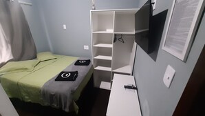 Un dormitorio pequeño y ordenado con una cama individual, un armario blanco y un escritorio con una silla.