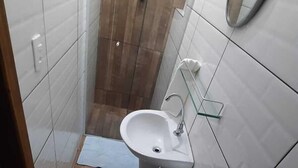 Un baño pequeño y estrecho con azulejos blancos, un lavamanos blanco, un inodoro y un espejo en la pared.