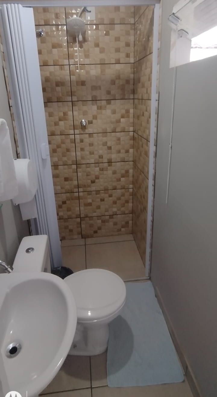 Et badeværelse med bruser, toilet og vask.