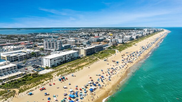 A coastal cityscape with a long sandy beach lined with numerous beach umbrellas and people. - Oceanfront 3 Bedroom Condo - Steps to the beach and ocean. Perfecty located on 119th Street! Sandy Square 304 (Ocean City)