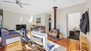 A modern living room with a sofa, armchair, and a fireplace. - Broadwater Waves family home, short walk to beach (Cape Woolamai)