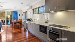 A modern kitchen with grey cabinets, a dishwasher, an oven, and a built-in microwave. - Broadwater Waves family home, short walk to beach (Cape Woolamai)