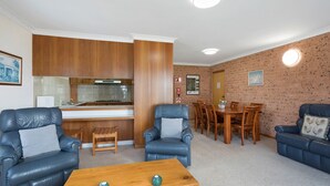 A compact living space with a kitchen, dining area, and seating. - Views on Ballingalla (Narooma)