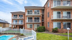 A multi-story apartment building with balconies, a swimming pool, and a well-maintained lawn. - Views on Ballingalla (Narooma)