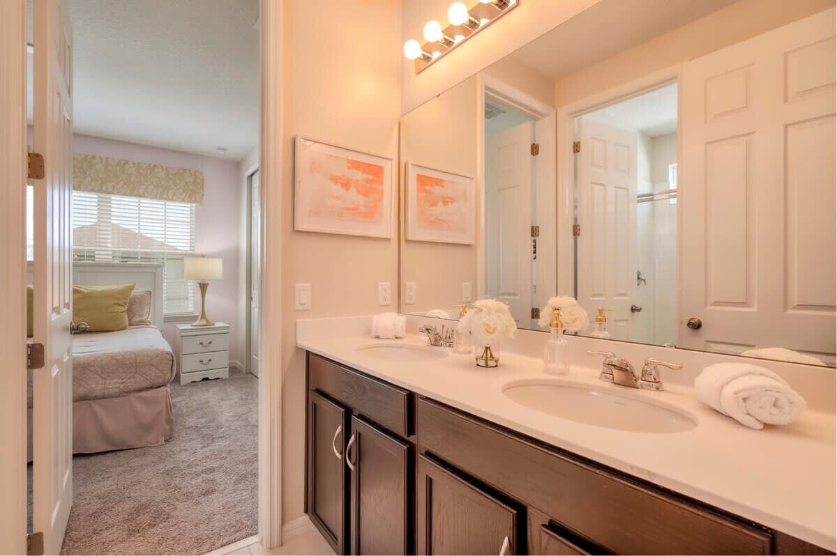 A bathroom with a double sink, a large mirror, and a walk-in closet.