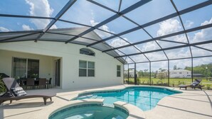 A covered outdoor swimming pool with lounge chairs, a patio table, and a view of a residential area. - Last Minute Disney Getaway! Private Pool, Hot Tub & Game Room. Book Now! #41843 (Orlando)