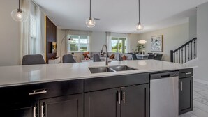 A modern kitchen with a central island, black cabinets, and pendant lighting. - Last Minute Disney! Private Pool, Game Room & Themed Bedrooms. Book Now! #41935 (Orlando)