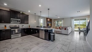 A modern kitchen with dark cabinets, stainless steel appliances, and a central island. - Last Minute Disney! Private Pool, Game Room & Themed Bedrooms. Book Now! #41935 (Orlando)
