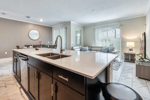 A modern kitchen with a large island, double sink, and dark cabinetry. - Last Minute Disney Getaway! Townhouse with Private Pool. Book Now! #46733 (Orlando)