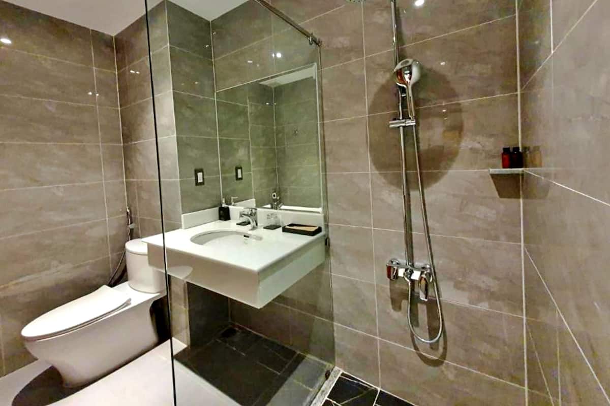 Une salle de bain moderne avec une douche à parois de verre, un lavabo blanc et des toilettes.