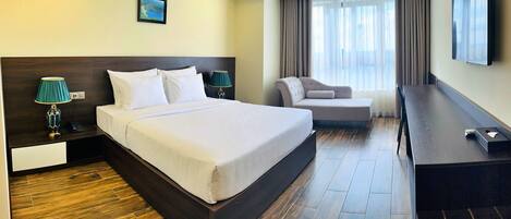 Habitación de hotel con una cama grande, dos mesitas de noche con lámparas, un escritorio, una silla y un televisor.