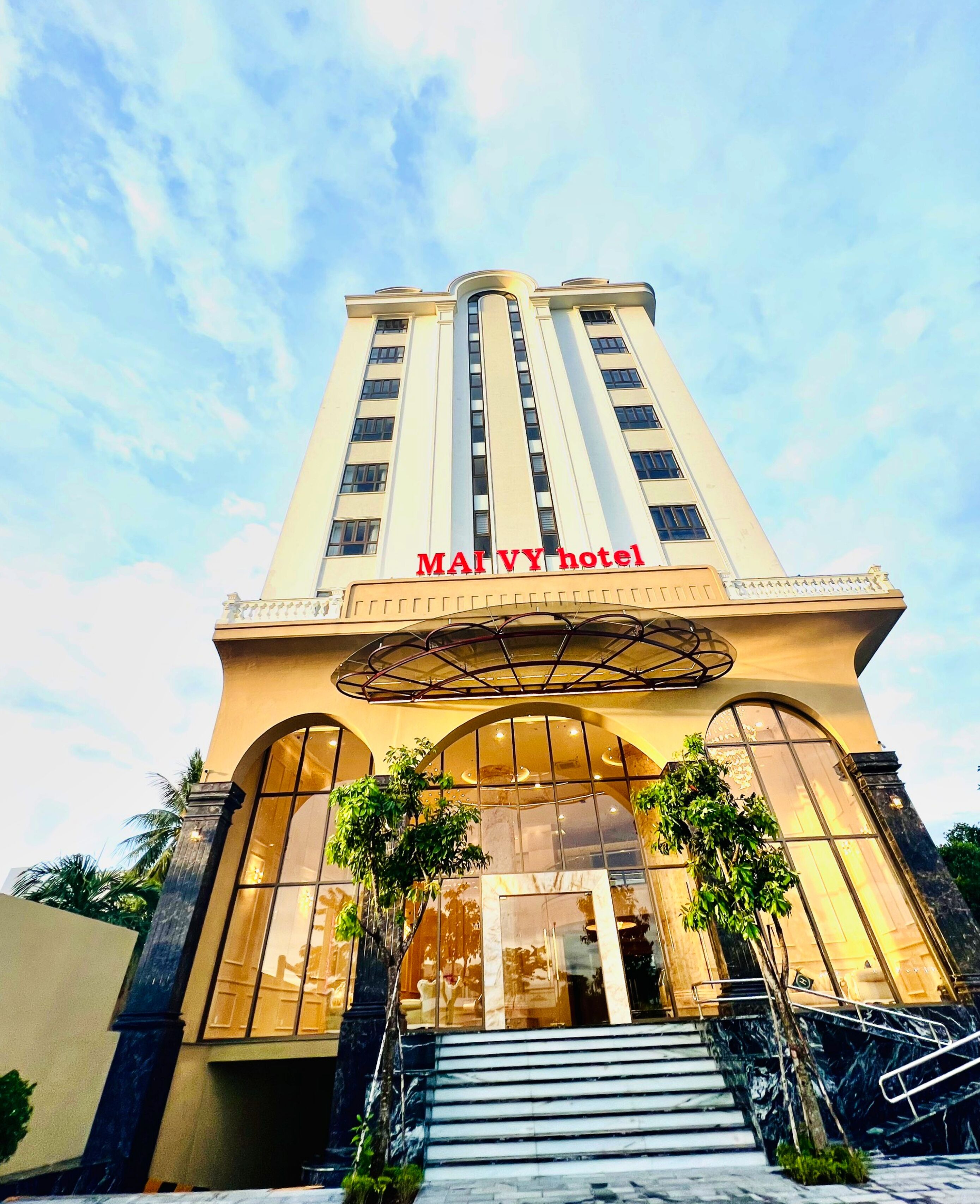 A hotel with a prominent entrance, large windows, and a clear sky.