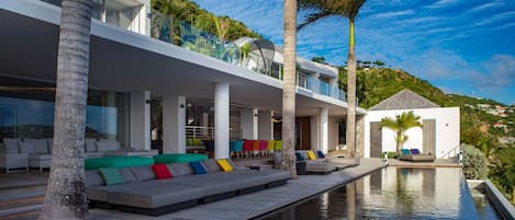 A modern villa with a pool, outdoor seating, and a view of the surrounding landscape.