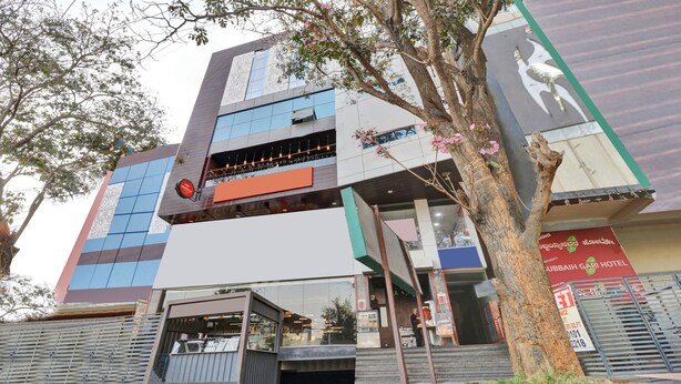Um hotel moderno com fachada de vidro, um restaurante visível e uma placa com o nome 