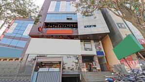 Um edifício comercial com vários andares, incluindo um restaurante no andar térreo, com uma escadaria visível que leva à entrada.