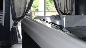 A bathroom with a bathtub, a window with sheer curtains, and a towel rack. - Charming love room Althea (Fontenay-le-Comte)