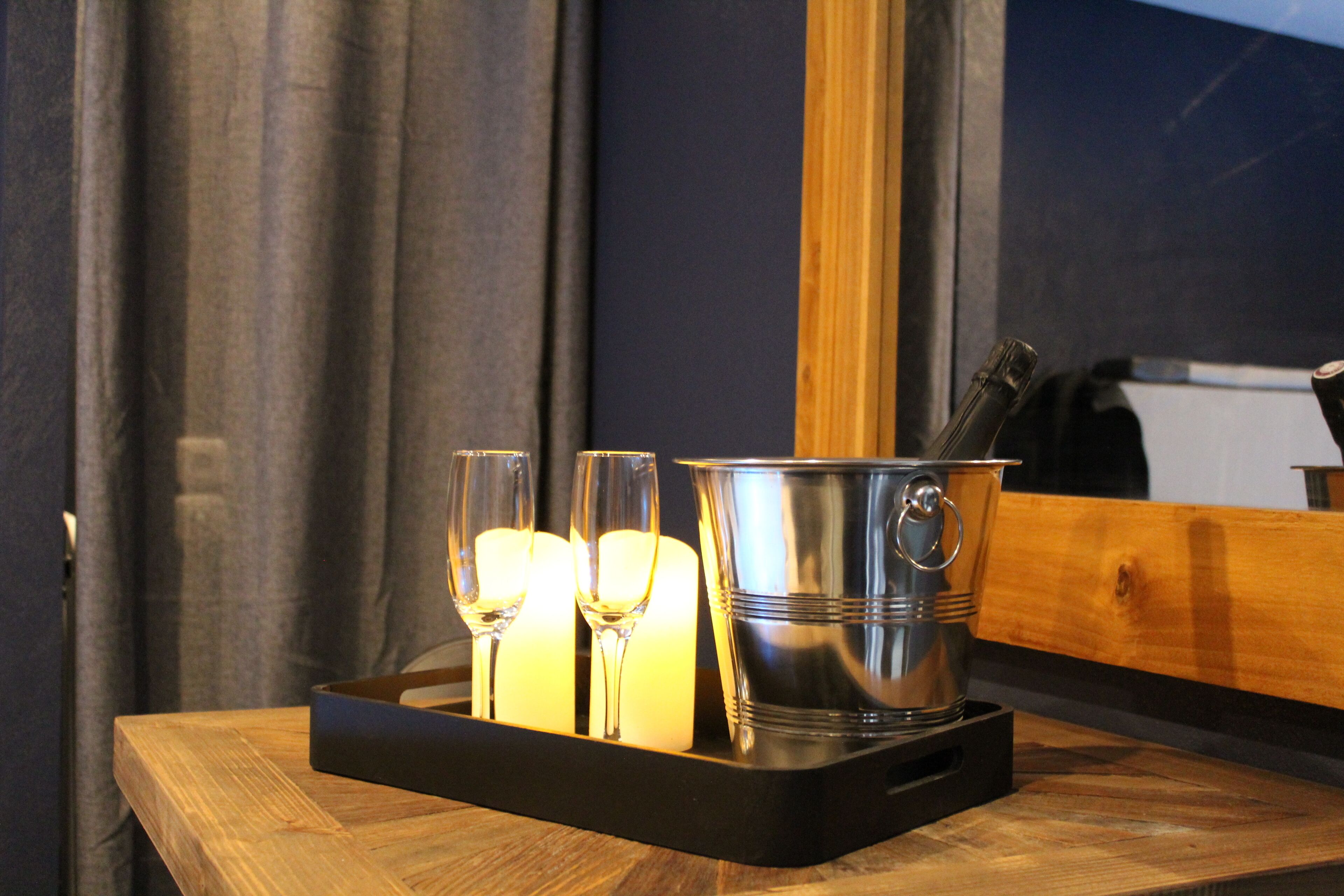 Una bandeja con dos vasos y dos velas sobre una mesa de madera.