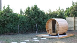 A wooden barrel-shaped structure with a door, set on a grassy area with stepping stones leading to it. - Charming love room Althea (Fontenay-le-Comte)