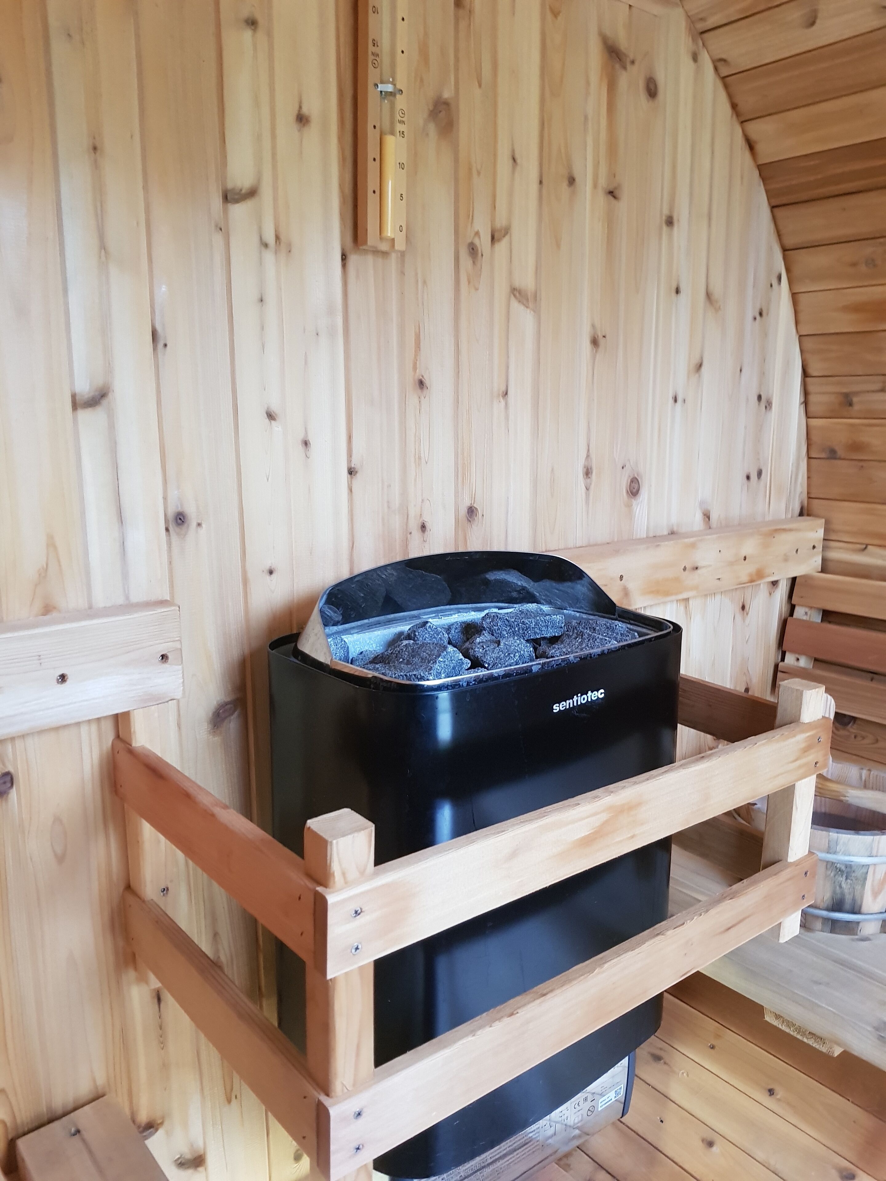 A black stove with a metal grate on top, placed on a wooden bench inside a wooden cabin.