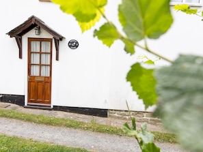 A white cottage with a wooden door and a small window, a stone wall, and a sign indicating it is number 3. - Cosy cottage with views over the Shropshire hills - Pass the Keys (Ludlow)