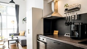 A modern kitchen with a built-in oven, a coffee machine, and a hanging utensil rack.