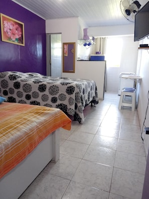 A room with two beds, a small kitchenette, and a TV. - GUEST HOUSE RENASCER K&W (Cabo Frio)