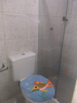 A bathroom with a toilet, a shower stall, and a glass door. - GUEST HOUSE RENASCER K&W (Cabo Frio)