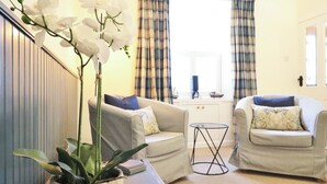 A living room with two armchairs, a small table, and a potted plant. - 2 bedroom accommodation in Kirkcudbright (Kirkcudbright)