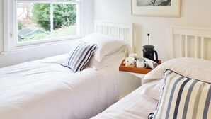 A bedroom with two single beds, a window with a view of greenery, a bedside table with a kettle, and a framed picture on the wall. - 2 bedroom accommodation in Kirkcudbright (Kirkcudbright)