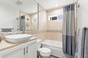 Features a large vessel sink, standalone toilet, and bathtub.