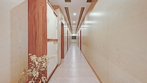 A long, narrow hallway with marble walls and wooden paneling on one side. - Itsy Hotels Sri Sai Grand Inn (Vijayawada)