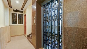A hallway with a tiled floor, a door with a metal security gate, and a window with a view of the outside. - Itsy Hotels Sri Sai Grand Inn (Vijayawada)