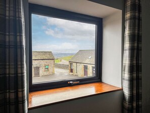 A window with a view of stone buildings and a clear sky.