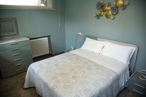 Ein Schlafzimmer mit Bett, Schminktisch, Heizkörper und Wanddekoration.