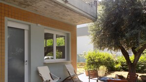 Une terrasse avec deux chaises longues, une table et un pot de fleurs.