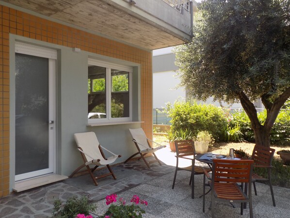Eine Terrasse mit zwei Liegestühlen, einem Tisch und einem Blumentopf.