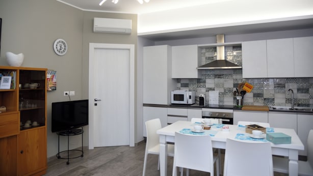 Une cuisine moderne avec des meubles blancs, un four à micro-ondes et un coin repas comprenant des chaises et une table, le tout dans des tons blancs.
