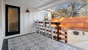 A covered outdoor seating area with a patterned floor, white walls, and a wooden fence. - BEAUTIFULLY Remodeled Home, Close to Downtown!! (Paso Robles)