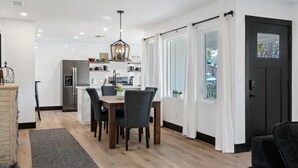 A modern kitchen with a dining area, white cabinetry, and a black door. - BEAUTIFULLY Remodeled Home, Close to Downtown!! (Paso Robles)