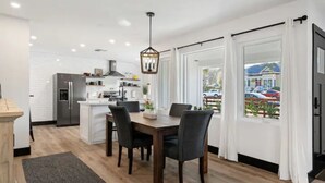 A modern kitchen with white cabinetry, a central island, and a dining area with a wooden table and chairs. - BEAUTIFULLY Remodeled Home, Close to Downtown!! (Paso Robles)