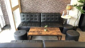 A modern lounge area with a black leather sofa, a wooden coffee table, and black ottomans. - Cool-innOTARU (Otaru)