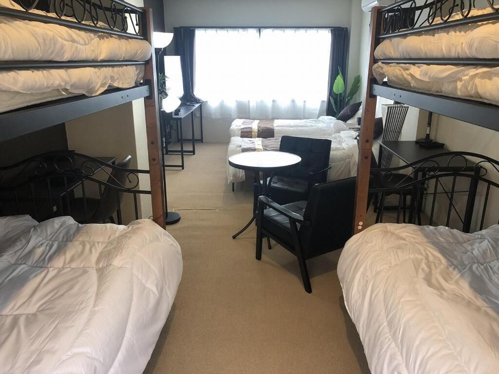 Una habitación de hotel con literas, una mesa redonda y un sofá.