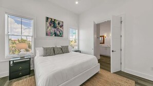 Un dormitorio con una cama grande, una mesita de noche, una lámpara y un cuadro en la pared.
