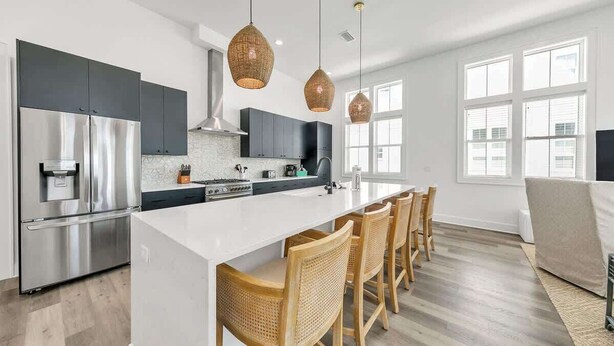 A modern kitchen with a central island, stainless steel appliances, and a dining area with wooden chairs.