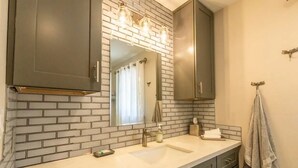 A bathroom with a white sink, dark cabinets, and a mirror above it.