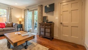 A living room with a sofa, coffee table, TV, and a door.