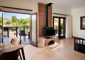 Una sala de estar moderna con chimenea de ladrillo, puertas de cristal correderas grandes y vistas a un jardín ajardinado.